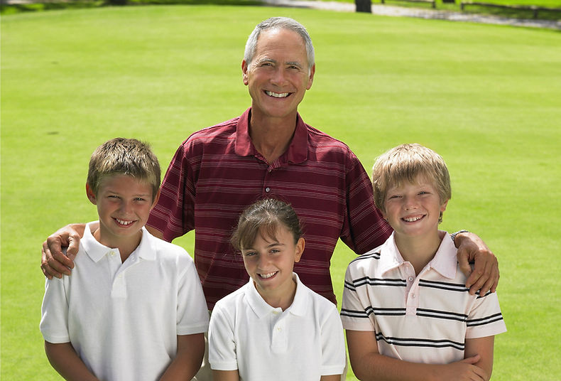 Golf instructor with three young golfers smiling on golf course